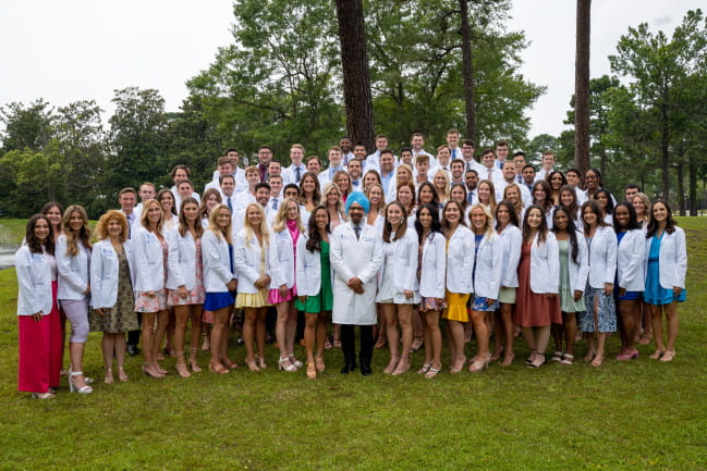 Students standing with Dr. Huja at white coat ceremony.