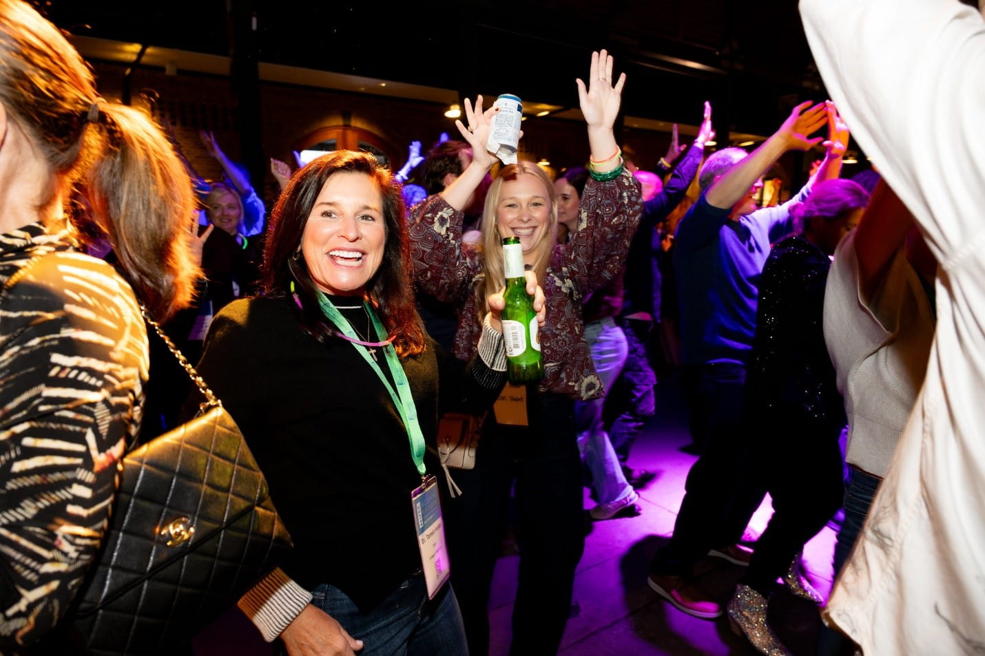  A group of people dancing at a party, drinks in hand 