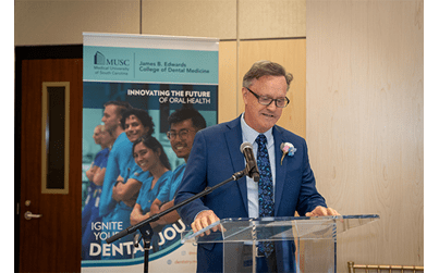 Dr. Boyd smiles as he shares prepared remarks from a podium in the lobby.