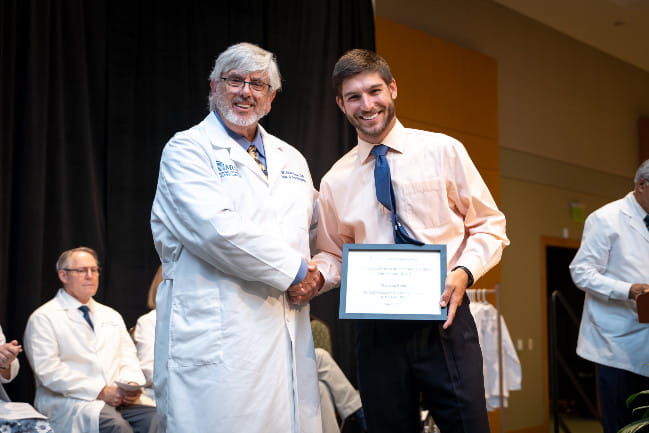 Madison Sharp smiles with his scholarship award he received during his White Coat Ceremony for the MUSC James B. Edwards College of Dental Medicine. 