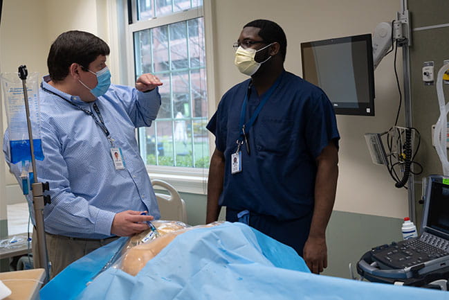 Dr. Eddie Kilb, Caucasian male, teaching an African American male student in the SIMS Center at MUSC
