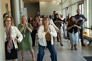 Group of adults in an impromptu exercise class in a hallway of an educational building