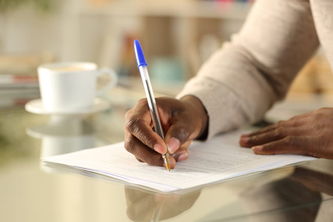 African-American man's hands shown filling out forms with a blue pen