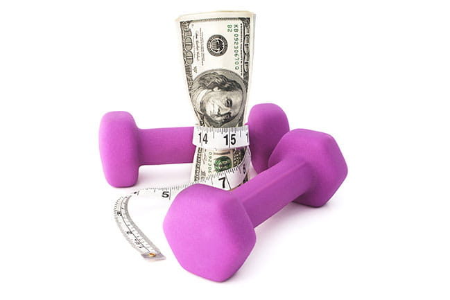 pink dumbells with tape measure around 100 dollar bill