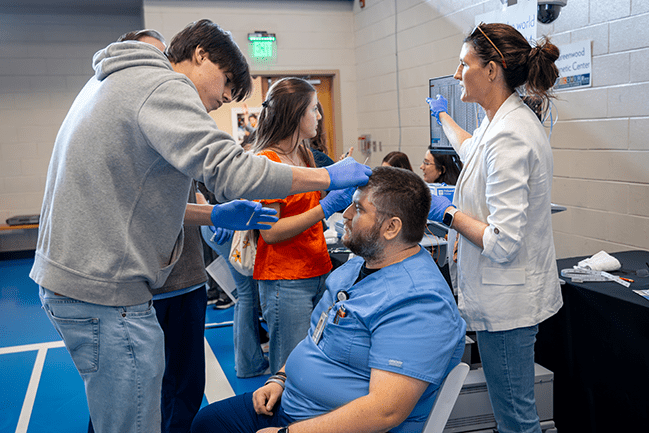Student tending fake wound on head of patient actor at DISCOVER MUSC event