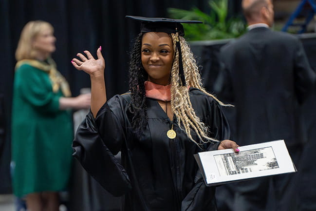Graduate waving after receiving MUSC diploma