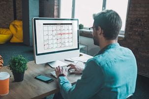 Man with glasses looking at a calendar on the computer