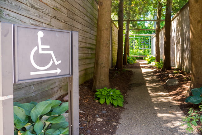 ADA compliance sign pointing to a handicap accessible pathway