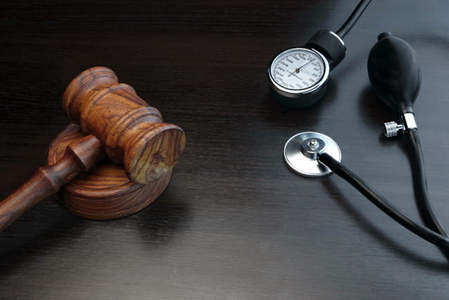 Judge's gavel and medical equipment laying on a black wooden table