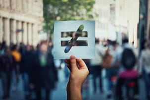 Person holding a paper sign with an inequality symbol on it