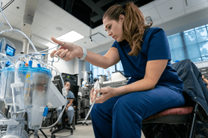 female perfusion student uses clamp on device in lab