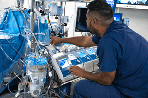 male perfusion student controls settings on device in lab