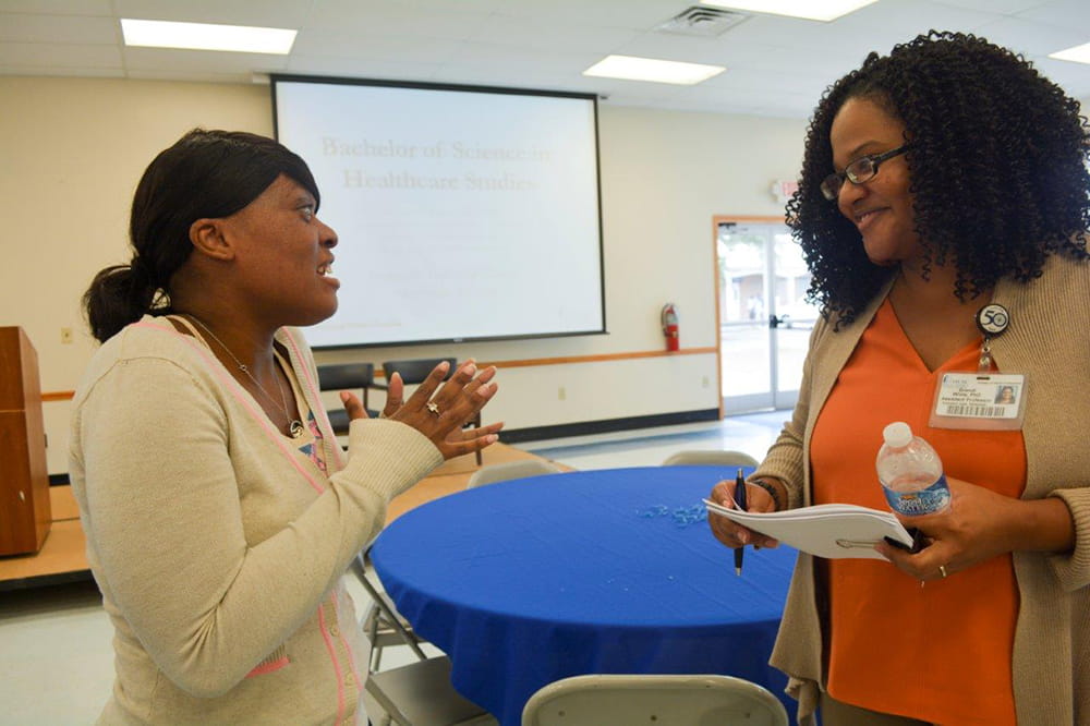 Denmark Technical College student Verta Whitaker talks with Brandi White at an information session.