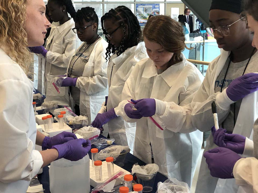 Lindsay McDonald, Ph.D., left, explains the banana DNA extraction experiment to girls at the Girls Day Out STEM camp.