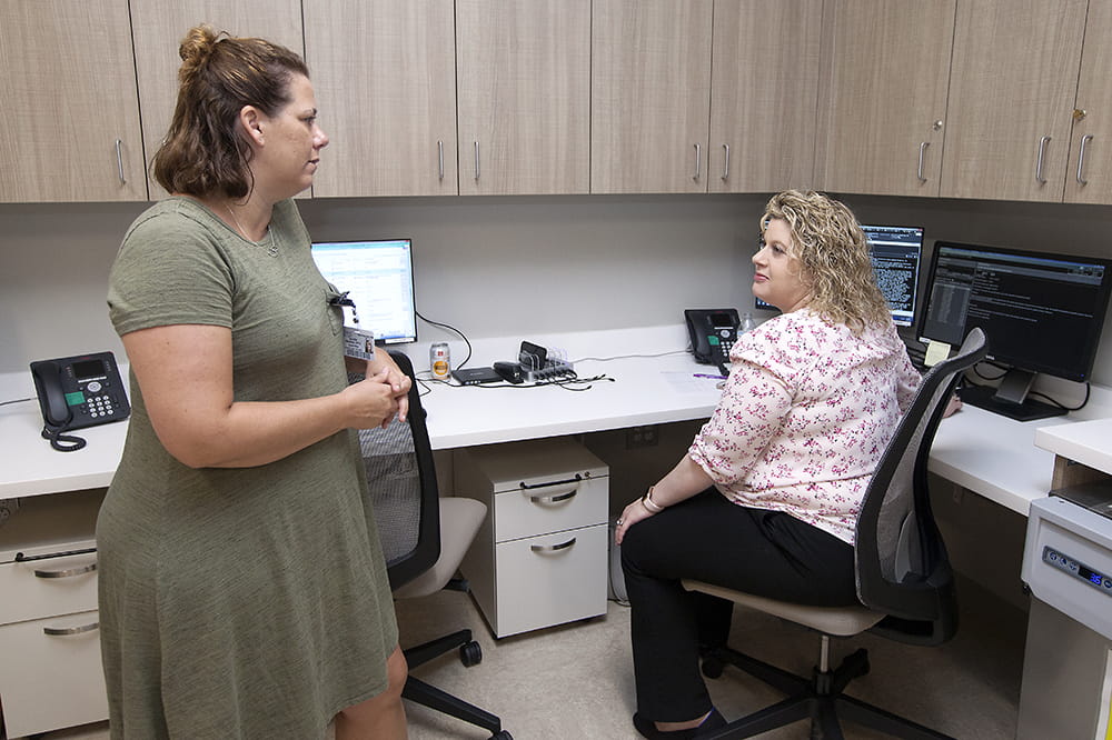 two women talk in an administrative area