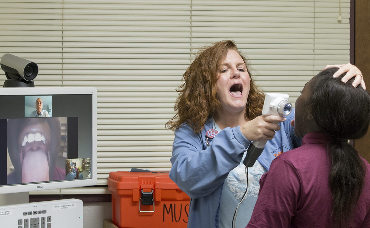 Nurse with mouth open showing student patient what she wants her to do