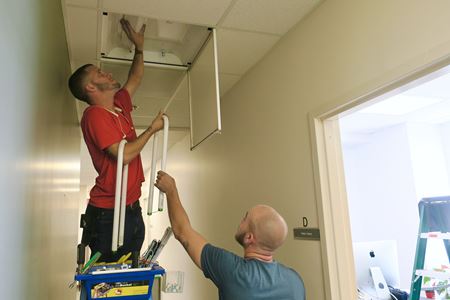 Electricians changing out fluorescent bulbs for LEDs inside MUSC's 135 Cannon Street facility