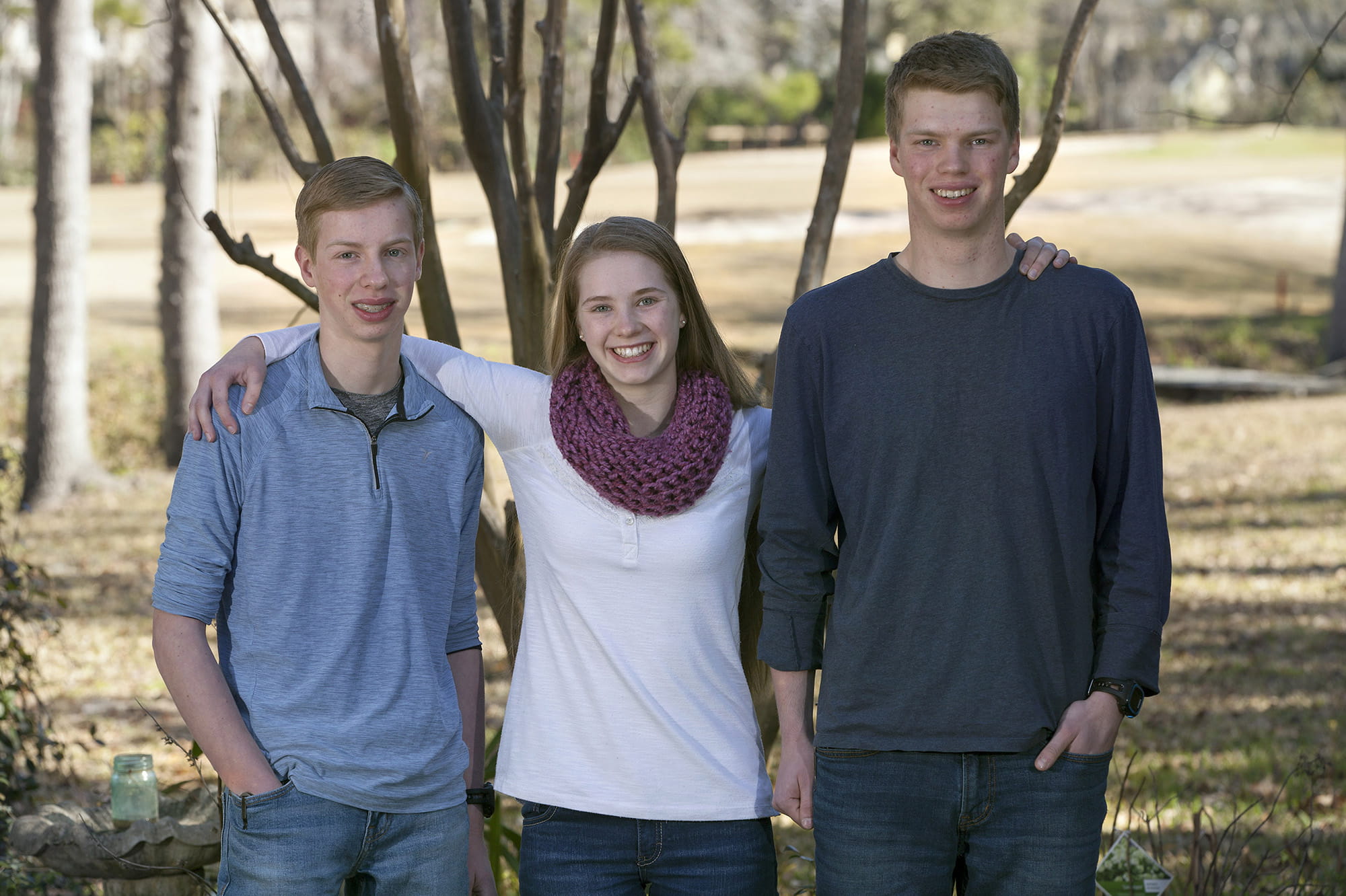 16-year-old triplets stand for photo in their back yard