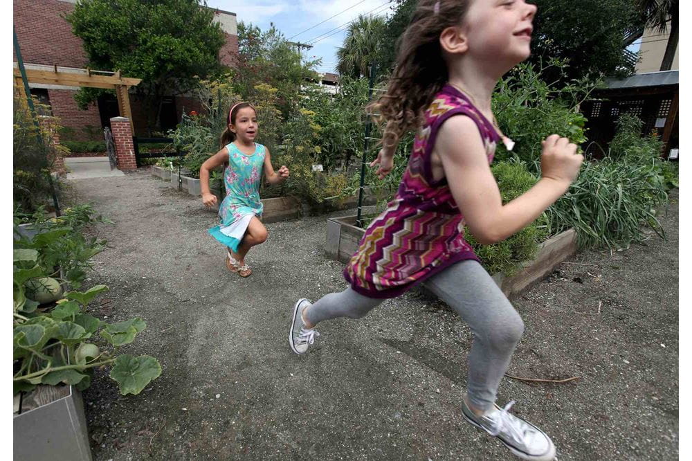 Two kids run through an outdoor garden