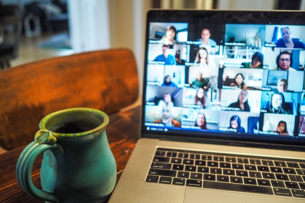 Coffee mug on table next to computer with a zoom meeting on screen