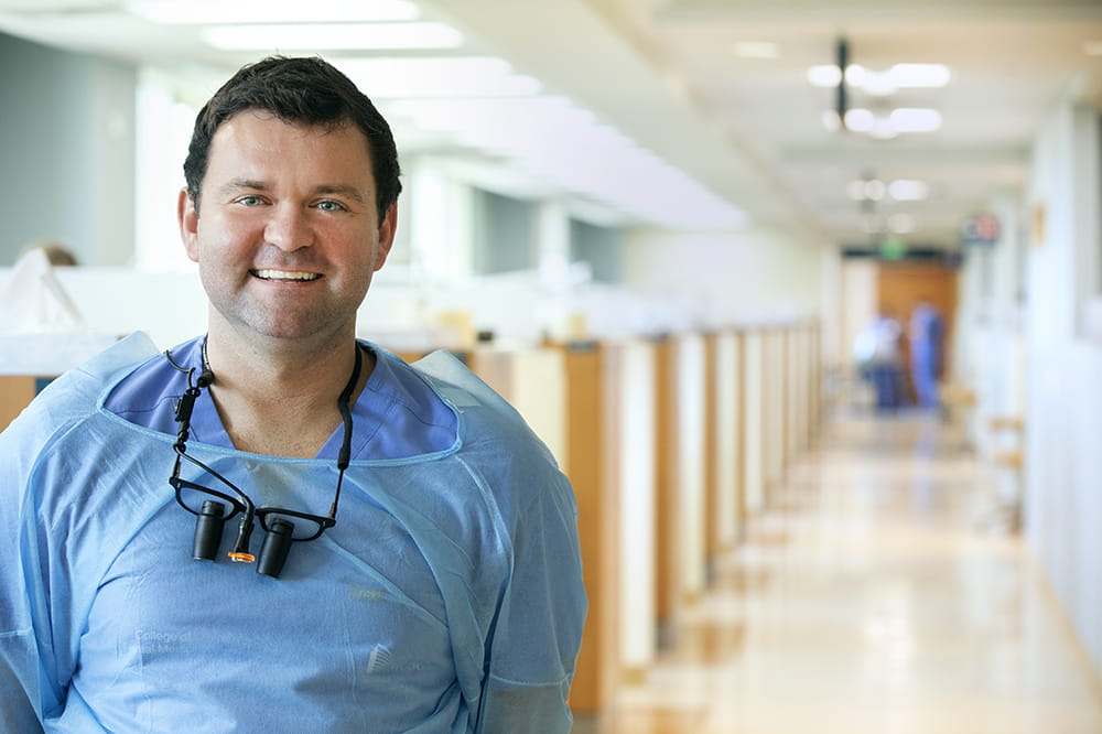 Keith Tormey is wearing scrubs and smiling in a hallway.