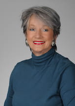Mugshot of woman with gray hair wearing a dark blue turtleneck