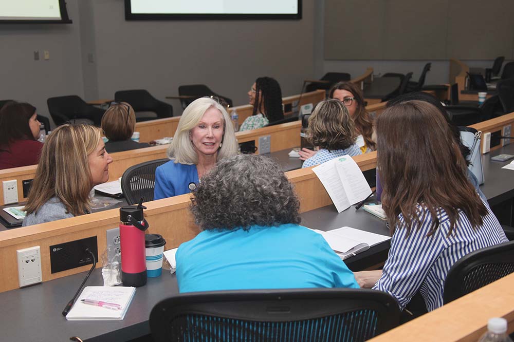 Four women face each other in an auditorium for a discussion.