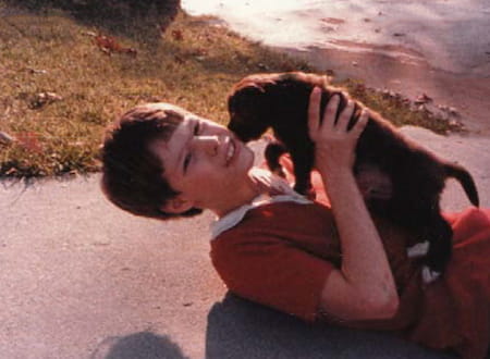 A young boy lying on the ground holding a puppy