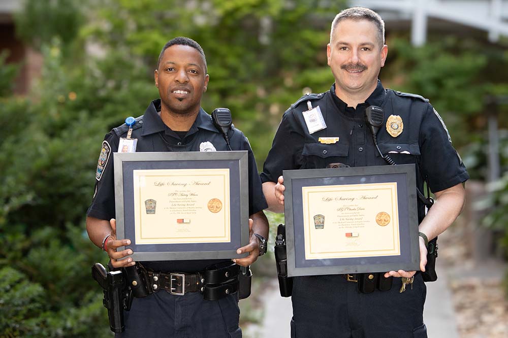 Public Safety Officer Aubrey Wilson and Sgt. Charles Davis hold awards they received for saving a man's life.